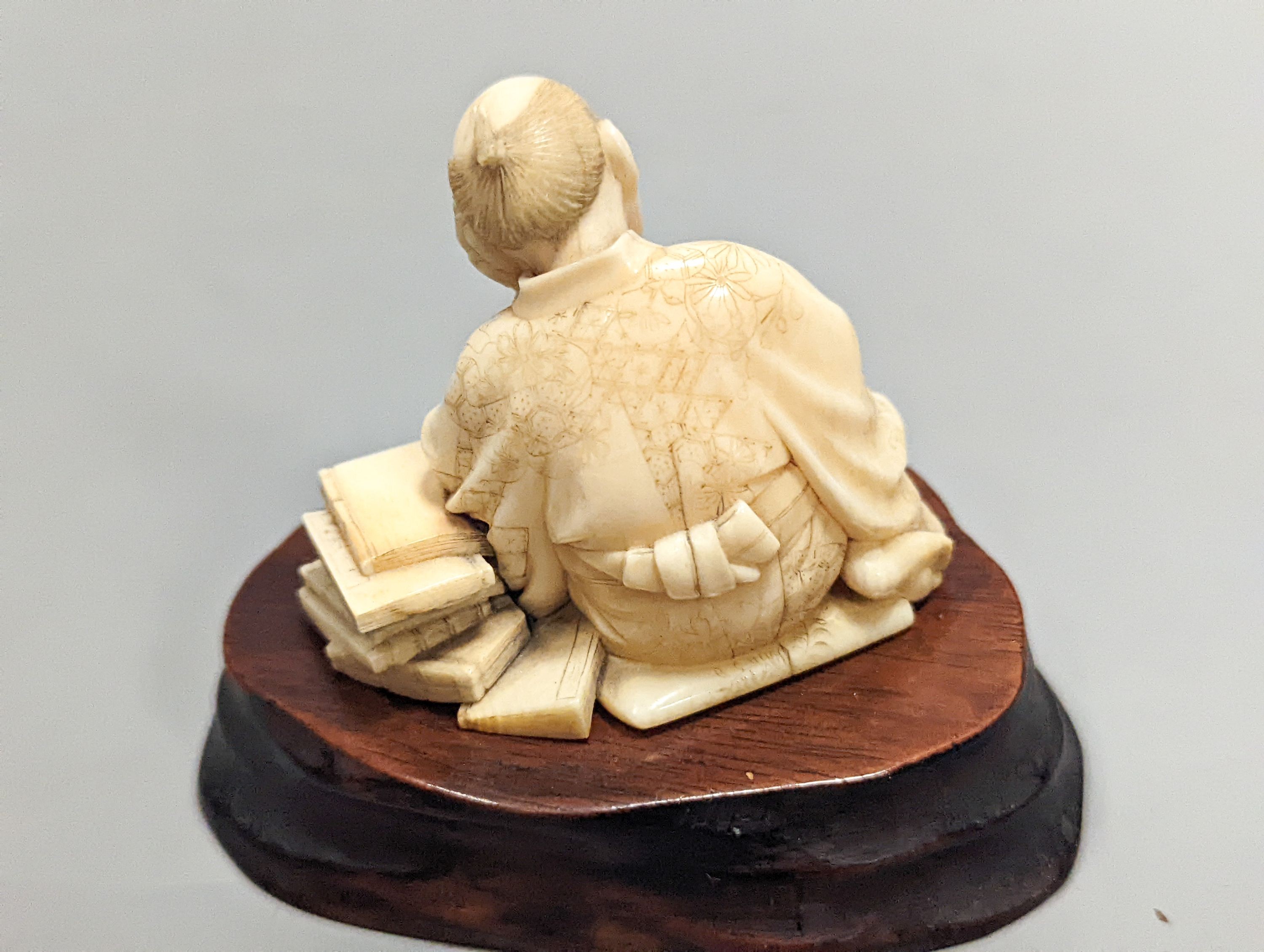 A Japanese ivory okimono of a scholar, Meiji period, signed, 5 cms high not including stand.